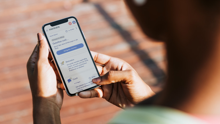 Eine Userin blickt auf ein Smartphone mit geöffneter Mentalis-App