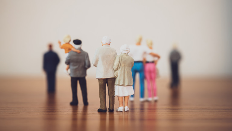Mehrere Paare und Menschen unterschiedlichen Alters stehen als Miniaturfiguren abgebildet auf einer Fläche aus Holz vor einem unscharfen Horizont als Motiv für das Einführungssymposium "Die Zukunft ist alt – Chancen einer modernen Geriatrie" von Priv.-Doz. Dr. med. Markus Gödel, Chefarzt im Albertinen Zentrum für Altersmedizin im Albertinen Krankenhaus in Hamburg.