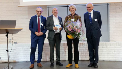 Ralf Zastrau, Prof. Dr. Hans-Peter Meier-Baumgartner und Prof. Dr. Wolfgang von Renteln-Kruse stehen nebeneinander mit Dr. Ulrike Dapp, die einen Blumenstrauße in den Händen hält, auf der Bühne bei der Jubiläumsveranstaltung mit Symposium und einer Dankesveranstaltung zum 25-jährige Bestehen der LUCAS Langzeit-Kohortenstudie im Hamburger Albertinen Haus und Kirche am Albertinen Krankenhaus.