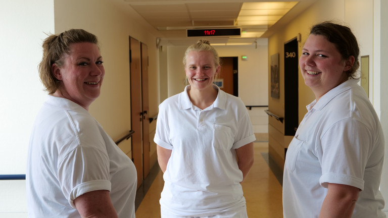 Drei neorologische Therapeutinnen stehen in weißer Funktionskleidung auf einem Krankenhausflur und lächeln in die Kamera im Interdisziplinären Therapiezentrum im Albertinen Krankenhaus Hamburg Drei neorologische Therapeutinnen stehen in weißer Funktionskleidung auf einem Krankenhausflur und lächeln in die Kamera im Interdisziplinären Therapiezentrum im Albertinen Krankenhaus Hamburg