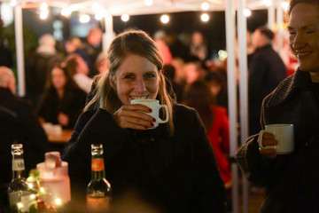Besucherin des Weihnachtsmarkts der Immanuel Albertinen Diakonie hält eine Tasse Punsch in stimmungsvoller Beleuchtung
