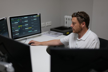 Arzt sitzt an einem Arbeitsplatz der Zentralen Notaufnahme und betrachtet die Vitaldaten mehrerer Patienten auf einem Monitor.