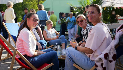 Vier Besucherinnen sitzen auf Sitzliegen und blicken in die Kamera beim Albertinen-Sommerfest für die Mitarbeitenden aus den unterschiedlichen Einrichtungen der Immanuel Albertinen Diakonie am Standort Schnelsen auf dem Platz vor der Kirche am Albertinen Krankenhaus.