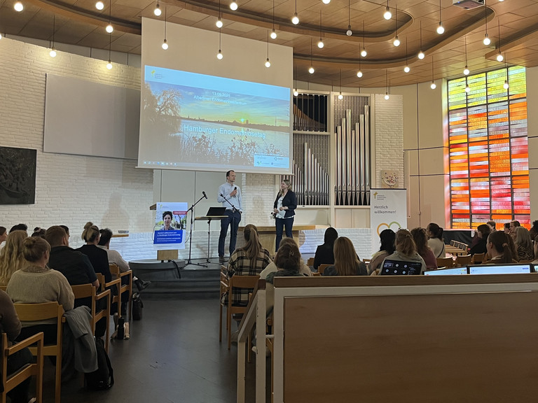 Blick über die Sitzreihen zur Bühne mit Leinwand in der Kirche am Krankenhaus beim zweiten Hamburger Endometriosetag 2025 der Klinik für Gynäkologie und Geburtshilfe im Albertinen Krankenhaus Blick über die Sitzreihen zur Bühne mit Leinwand in der Kirche am Krankenhaus beim zweiten Hamburger Endometriosetag 2025 der Klinik für Gynäkologie und Geburtshilfe im Albertinen Krankenhaus