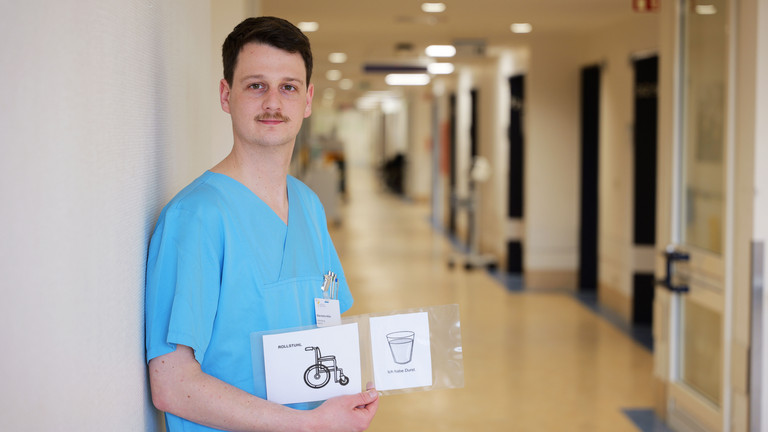 Kilian Müller, Stationsleitung der neurologischen Frührehabilitation im Albertinen Krankenhaus, zeigt Piktogramme zur Unterstützung der Kommunikation mit Patientinnen und Patienten nach Schlaganfall