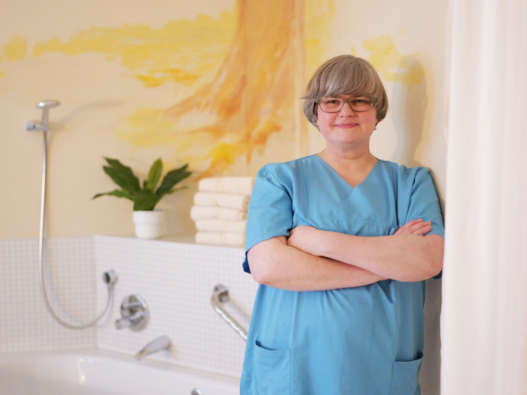Clarissa Richter, Leitende Hebamme in der Klinik für Gynäkologie und Geburtshilfe im Albertinen Krankenhaus, steht in blauer Funktionskleidung im neuen Hebammenkreißsaal mit warmen, orangefarbenen Wandtönen und einer Geburtswanne im Hintergrund und blickt in die Kamera. Clarissa Richter, Leitende Hebamme in der Klinik für Gynäkologie und Geburtshilfe im Albertinen Krankenhaus, steht in blauer Funktionskleidung im neuen Hebammenkreißsaal mit warmen, orangefarbenen Wandtönen und einer Geburtswanne im Hintergrund und blickt in die Kamera.