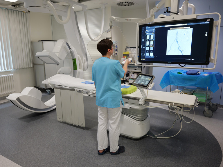 Eine Mitarbeiterin zeigt Diagnostikbilder auf dem Bildschirm des Angiographie Geräts