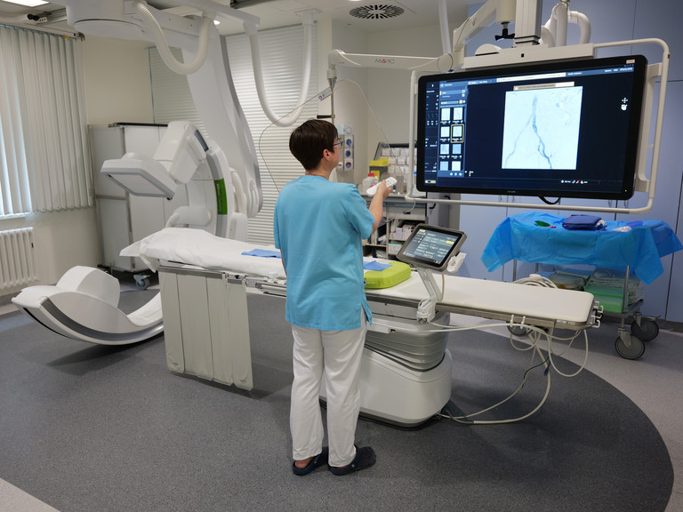 Eine Mitarbeiterin zeigt Diagnostikbilder auf dem Bildschirm des Angiographie Geräts