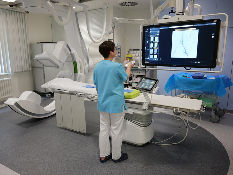 Eine Mitarbeiterin zeigt Diagnostikbilder auf dem Bildschirm des Angiographie Geräts
