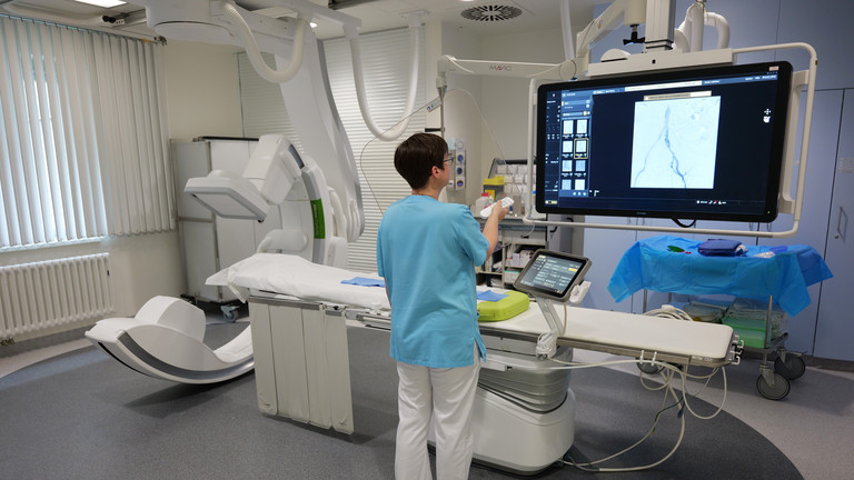 Eine Mitarbeiterin zeigt Diagnostikbilder auf dem Bildschirm des Angiographie Geräts
