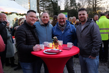 Mitarbeitende der Immanuel Albertinen Diakonie stehen gemeinsam am Stehtisch auf dem Weihnachtsmarkt