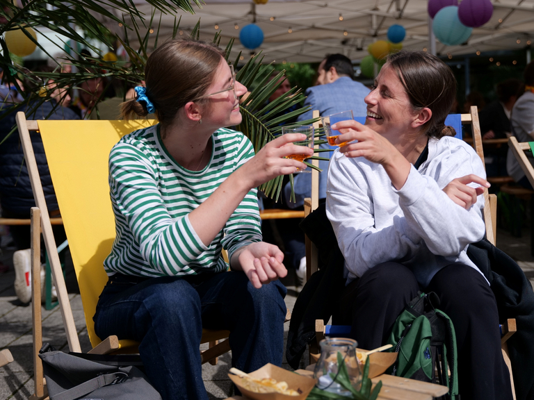 Zwei Mitarbeiterinnen stoßen mit einem Getränk beim Sommerfest in Schnelsen an