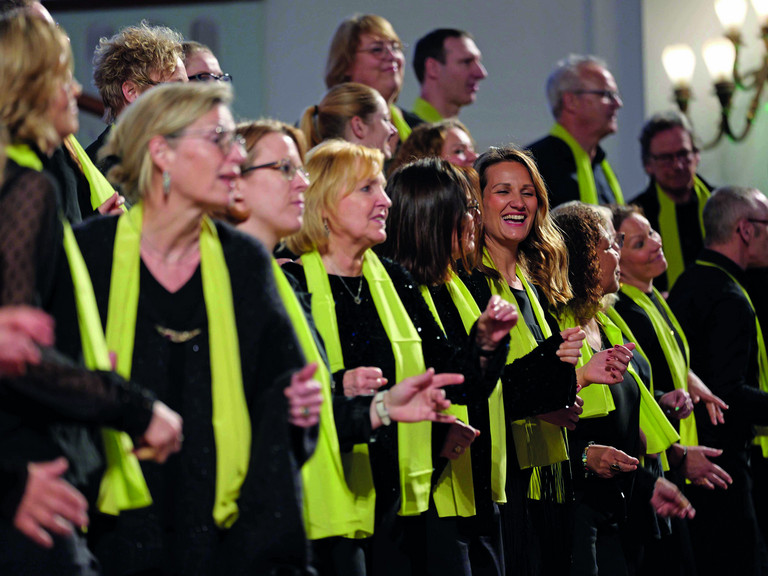 Mitarbeitende des Albertinen Gospelchors in festlich-bunten Gewändern beim Singen von Gospelliedern in der Kirche am Albertinen Krankenhaus in Hamburg-Schnelsen