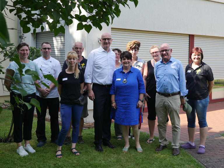Brandenburgs Ministerpräsident Dietmar Woidke auf einem Gruppenfoto mit Mitarbeitenden beim Besuch des Immanuel Suchthilfeverbunds Guben