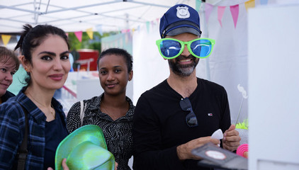 Drei Gäste mit bunten Hüten und einer extra großen Sonnenbrille beim Albertinen-Sommerfest für die Mitarbeitenden aus den unterschiedlichen Einrichtungen der Immanuel Albertinen Diakonie am Standort Schnelsen auf dem Platz vor der Kirche am Albertinen Krankenhaus.