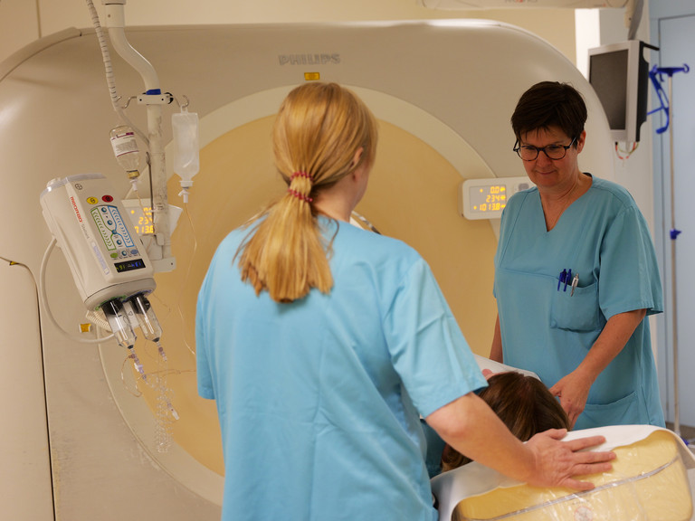 Zwei Mitarbeiterinnen betreuen eine Patientin in einem Computertomographie Gerät