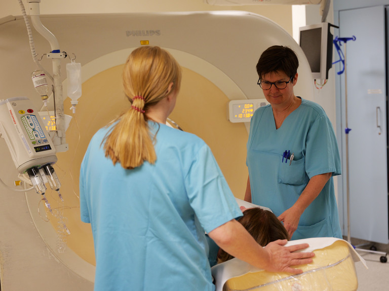 Zwei Mitarbeiterinnen betreuen eine Patientin in einem Computertomographie Gerät