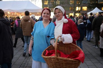 Pflegekraft und Weihnachtsfrau der Immanuel Albertinen Diakonie stehen lächelnd am Abend zusammen