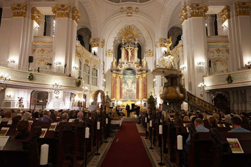 Der festlich beleuchtete Kirchensaal mit Empore und Sitzbänken beim 10. Herzbrücke-Benefizkonzert im Hamburger „Michel“ der Albertinen-Stiftung.