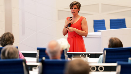 Dr. Julia Reinke, Leiterin des Endoprothetikzentrums in der Klinik für Unfallchirurgie und Orthopädie, steht mit einem Mikrofon vor den besetzten Stuhlreihen und hält einen Vortrag beim 1. Norderstedter Gelenktag für Betroffene und Interessierte zum Thema Arthrose im Rathaus Norderstedt. 