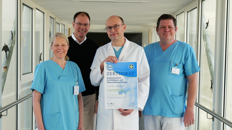 Vier Mitarbeitende des Evangelischen Amalie Sieveking Krankenhauses stehen nebeneinander und präsentieren die DGAV-Zertifizierung für das Zentrum für Endokrine Chirurgie: Dr. Denise Wittek, Geschäftsführer Andreas Schneider, Prof. Dr. Ernst von Dobschütz und Oberarzt Alexander Gnoss.