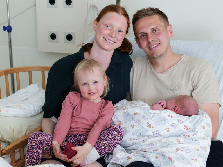Ingrid und Sebastian P. aus Elmshorn mit Tochter Ylvi und ihrem neugeborenen Sohn Momme sitzen gemeinsam auf dem Bett in einem Zimmer im Albertinen Geburtszentrum des Albertinen Krankenhauses in Hamburg-Schnelsen.
