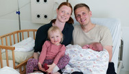 Ingrid und Sebastian P. aus Elmshorn mit Tochter Ylvi und ihrem neugeborenen Sohn Momme sitzen gemeinsam auf dem Bett in einem Zimmer im Albertinen Geburtszentrum des Albertinen Krankenhauses in Hamburg-Schnelsen.