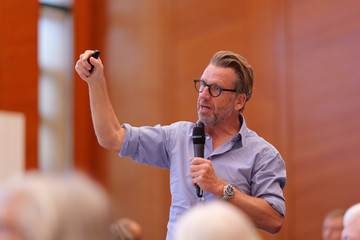 Chefarzt Prof. Dr. med. Thorsten Hanke bei seinem Vortrag mit einem Mikrofon in der Hand beim 2. Norderstedter Herz- und Gefäßtag mit dem Albertinen Herz- und Gefäßzentrum Hamburg im Norderstedter Rathaus