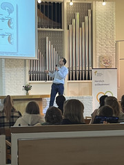 Chefarzt Prof. Dr. Rüdiger Klapdor blickt mit einem Mikrofon in der Hand auf die Leinwand bei seinem Vortrag beim zweiten Hamburger Endometriosetag 2025 der Klinik für Gynäkologie und Geburtshilfe im Albertinen Krankenhaus